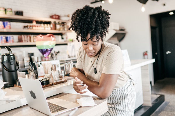 Woman working at table with laptop and cell phone